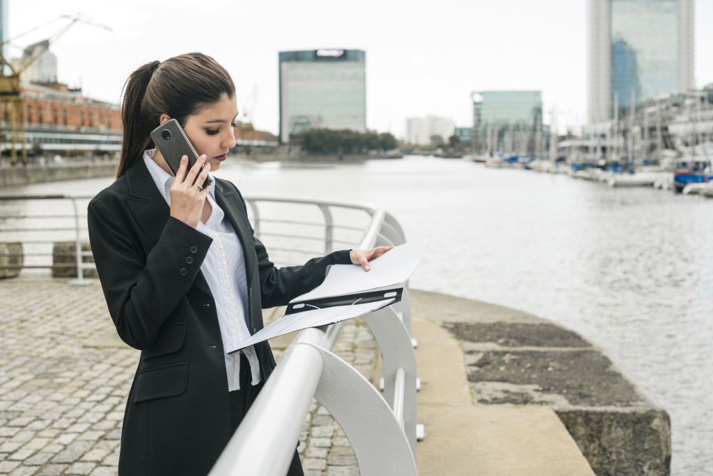 young-businesswoman-standing-harbor-talking-mobile-phone-while-looking-clipboard.jpg телефон